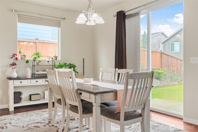 dining space featuring baseboards, an inviting chandelier, and wood finished floors