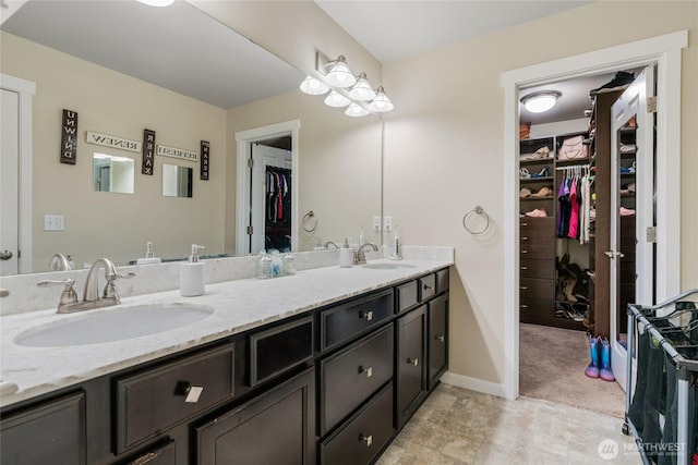 bathroom with a sink, baseboards, a spacious closet, and double vanity