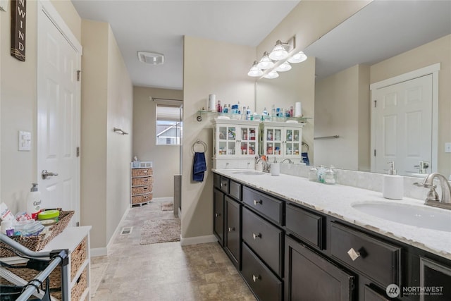 bathroom featuring double vanity, visible vents, baseboards, and a sink