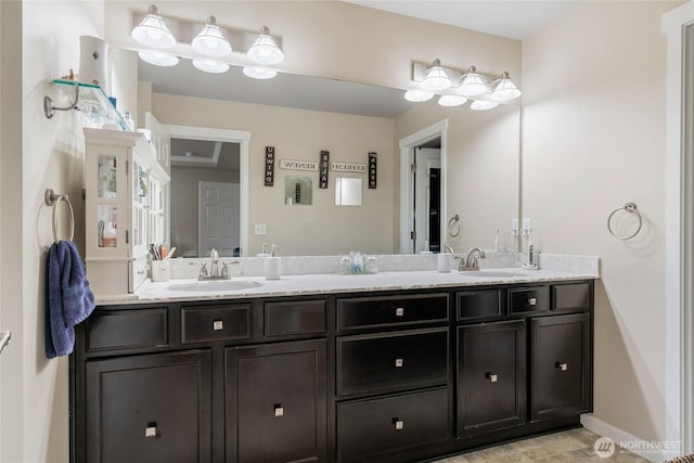 full bath featuring double vanity, baseboards, and a sink