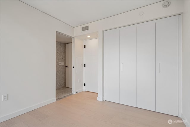 unfurnished bedroom with light hardwood / wood-style floors and a closet