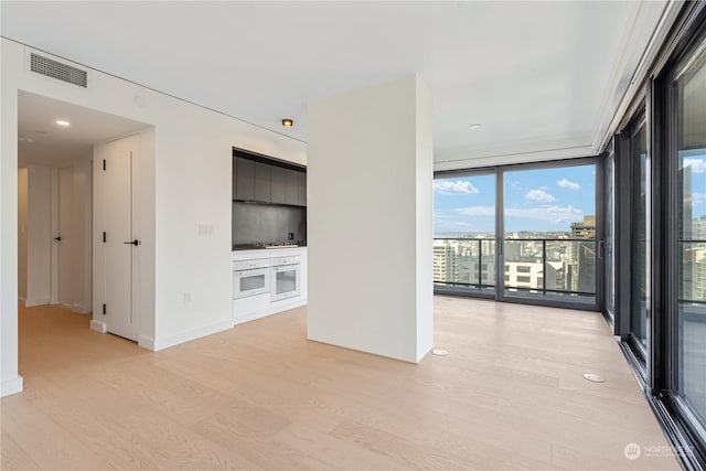 interior space with a wall of windows and light hardwood / wood-style flooring