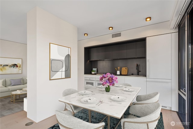 dining space with sink and light hardwood / wood-style flooring