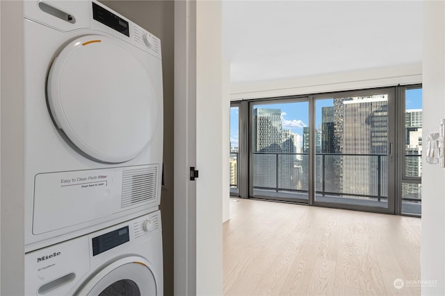 laundry area featuring stacked washer and dryer and light hardwood / wood-style flooring