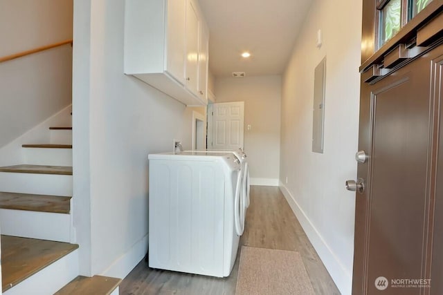 clothes washing area with laundry area, light wood-style floors, baseboards, electric panel, and washing machine and clothes dryer