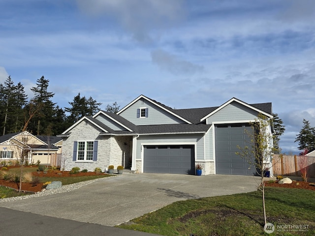 view of front of home featuring a garage, a shingled roof, fence, stone siding, and driveway