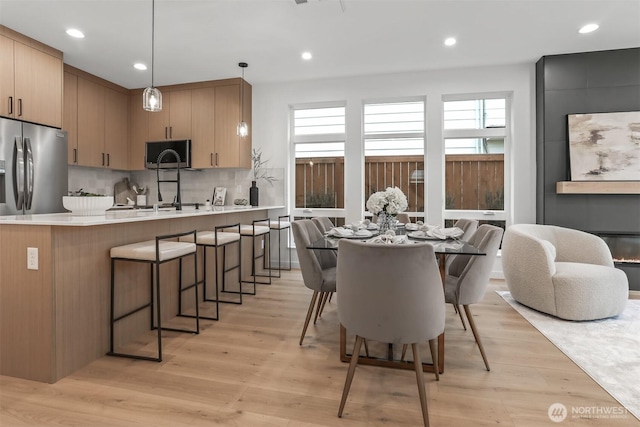 kitchen with appliances with stainless steel finishes, light countertops, hanging light fixtures, and light brown cabinetry