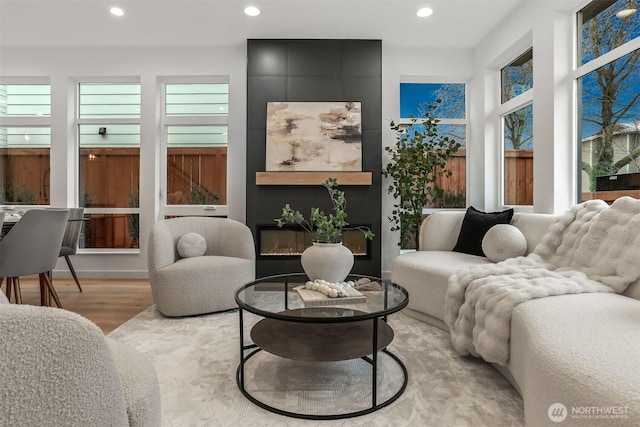 living room featuring recessed lighting, a large fireplace, plenty of natural light, and light wood-style flooring