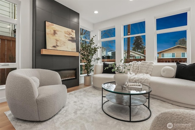 living area featuring a large fireplace, light wood-style flooring, and recessed lighting