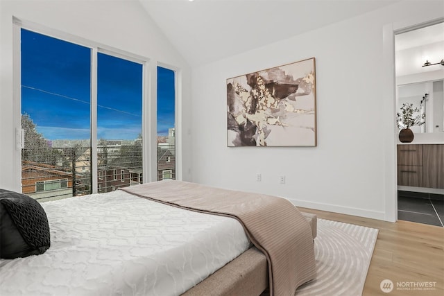 bedroom with lofted ceiling, light wood finished floors, and baseboards