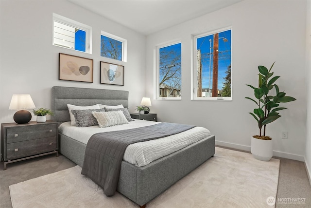 bedroom featuring multiple windows, light colored carpet, and baseboards