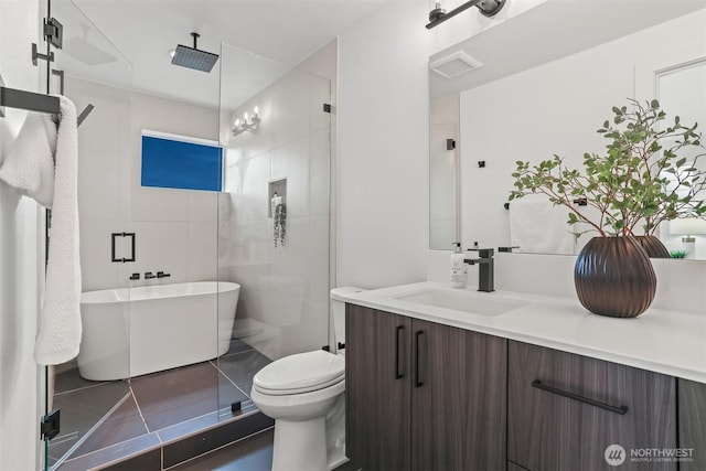 bathroom with toilet, a freestanding tub, a stall shower, and vanity