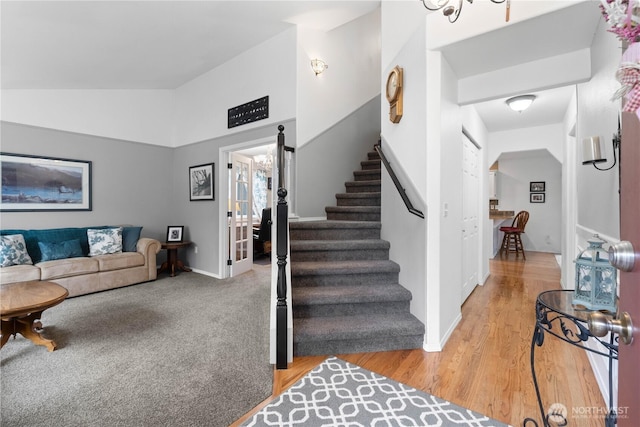 stairway with lofted ceiling, baseboards, and wood finished floors