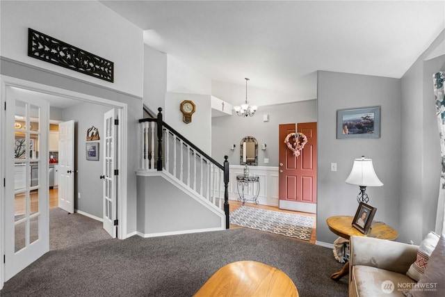 carpeted foyer entrance featuring lofted ceiling, a notable chandelier, baseboards, french doors, and stairway