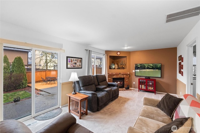 living area featuring baseboards, a brick fireplace, visible vents, and light colored carpet