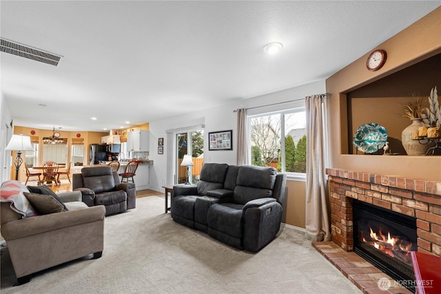 living area with light colored carpet, a brick fireplace, visible vents, and baseboards