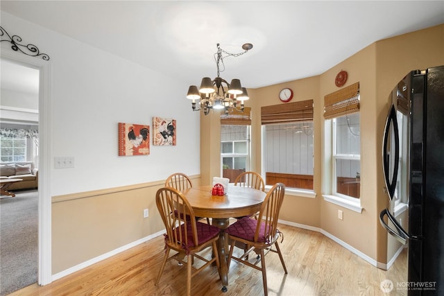 dining area with baseboards, light wood-type flooring, and an inviting chandelier