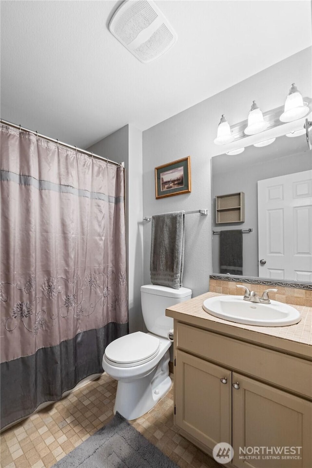 bathroom featuring visible vents, toilet, vanity, a shower with curtain, and tile patterned floors