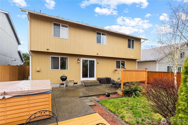 rear view of house featuring entry steps, fence, a hot tub, and a patio