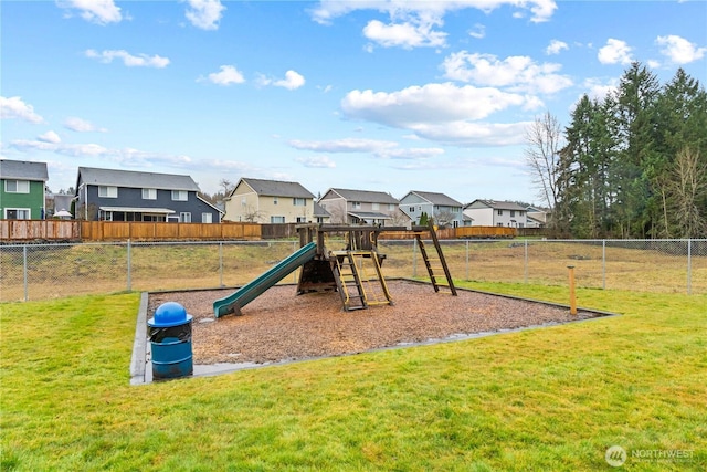 view of jungle gym featuring a lawn, fence, and a residential view