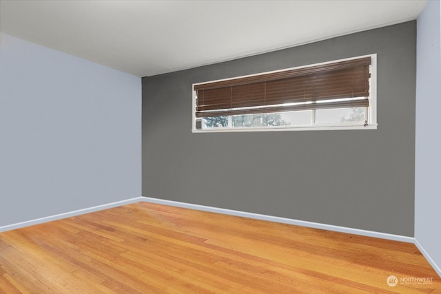 empty room featuring wood finished floors, baseboards, and a wealth of natural light