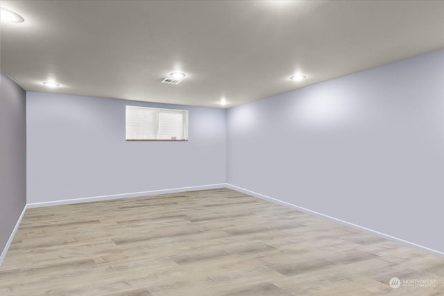 below grade area with light wood finished floors, visible vents, recessed lighting, and baseboards