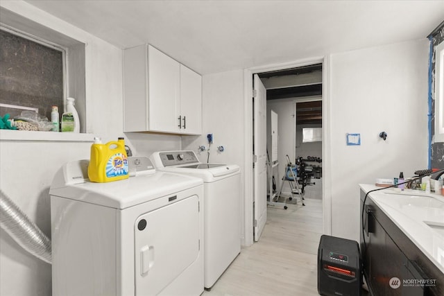 laundry area with cabinet space, light wood finished floors, and washer and clothes dryer