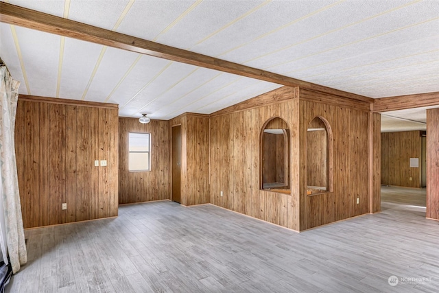 spare room featuring hardwood / wood-style floors, wooden walls, and vaulted ceiling with beams