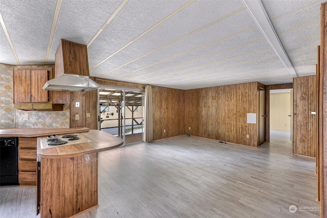 kitchen with white cooktop, custom exhaust hood, a textured ceiling, light hardwood / wood-style flooring, and wooden walls