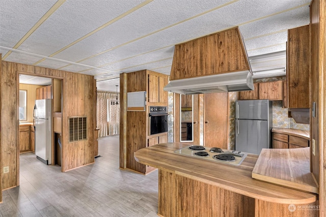 kitchen featuring white electric cooktop, stainless steel refrigerator, oven, custom exhaust hood, and fridge