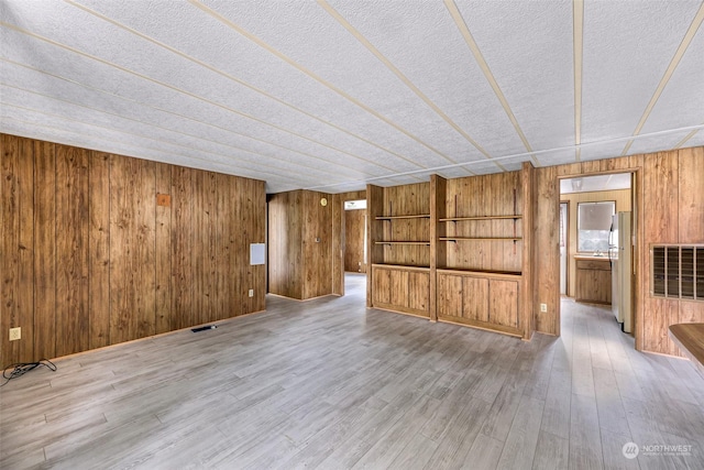 interior space featuring wood-type flooring, wooden walls, and a textured ceiling