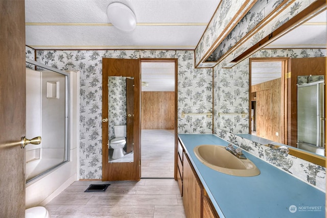 full bathroom with enclosed tub / shower combo, vanity, wood-type flooring, a textured ceiling, and toilet