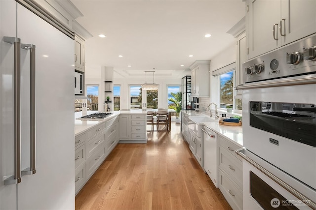 kitchen with white appliances, white cabinetry, sink, and decorative light fixtures