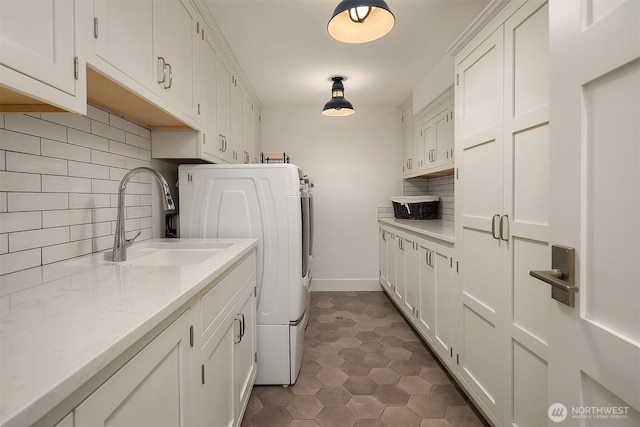 clothes washing area featuring cabinets, dark tile patterned floors, and sink