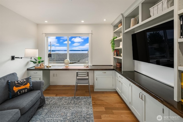 home office featuring light hardwood / wood-style flooring and built in desk