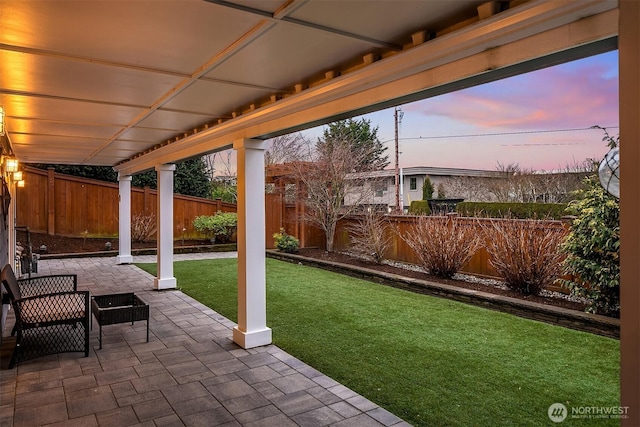 patio terrace at dusk featuring a yard