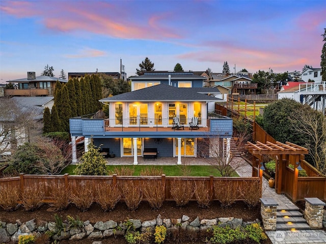 back house at dusk with a patio area and a balcony