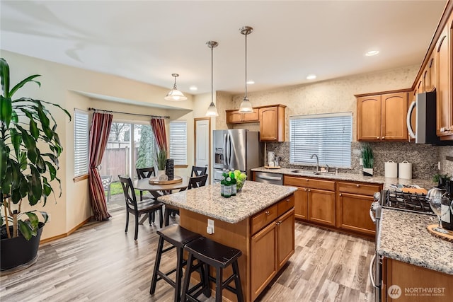 kitchen featuring a kitchen island, appliances with stainless steel finishes, decorative light fixtures, a sink, and backsplash