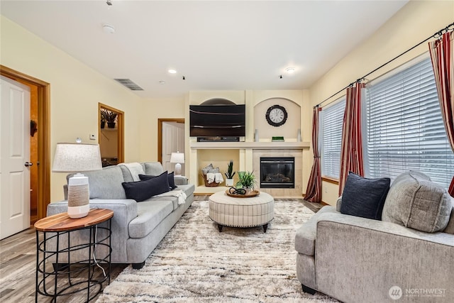 living room with visible vents, wood finished floors, and a tile fireplace