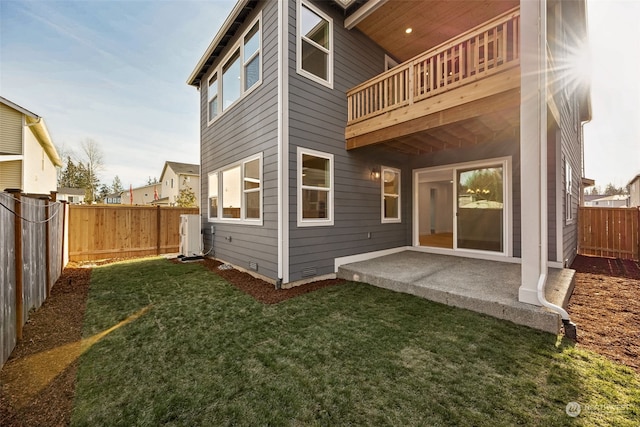 back of house featuring a balcony, a patio area, and a lawn