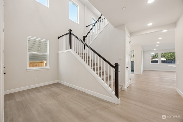 stairs featuring hardwood / wood-style flooring and a towering ceiling