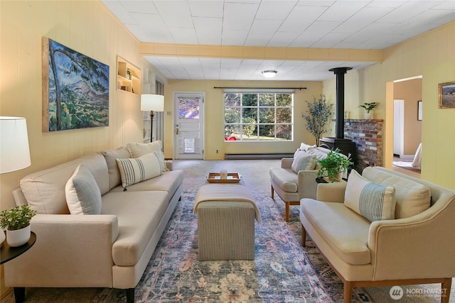 carpeted living room featuring a wood stove and baseboard heating