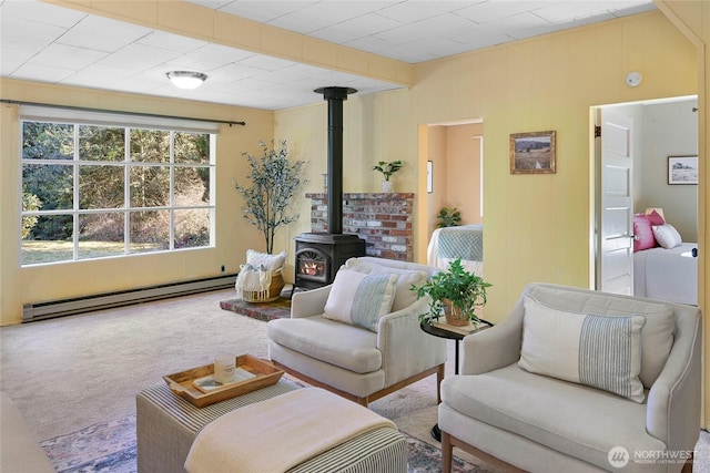 living room with a baseboard heating unit, a wood stove, and carpet