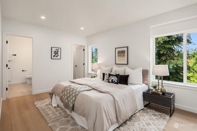 bedroom featuring ensuite bath and light wood-type flooring