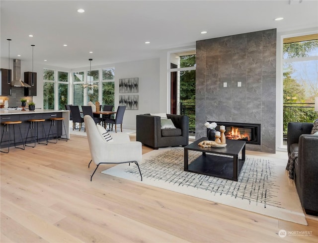 living room featuring floor to ceiling windows, a tiled fireplace, and light wood-type flooring