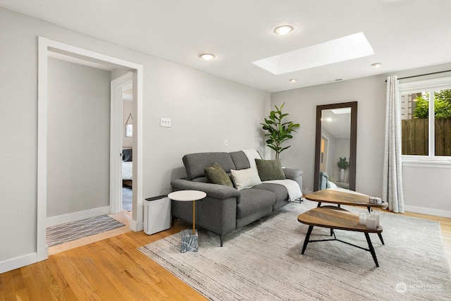 living room with light hardwood / wood-style flooring and a skylight