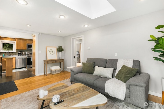 living room featuring dark wood-type flooring, sink, and a skylight