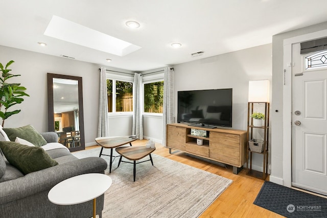 living room featuring light hardwood / wood-style flooring and a skylight