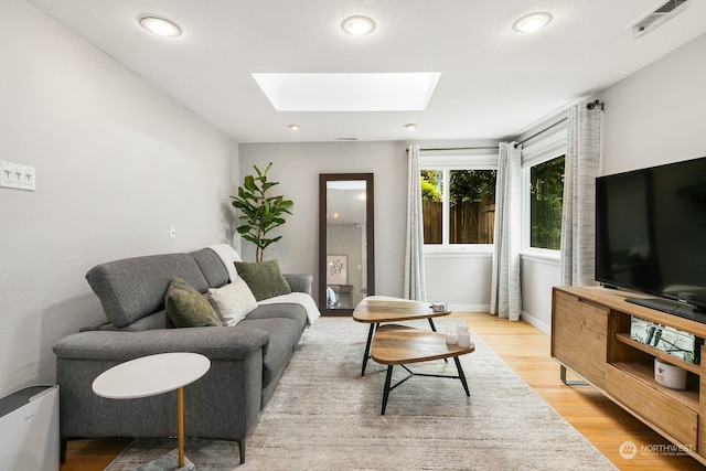 living room featuring a skylight and light hardwood / wood-style floors