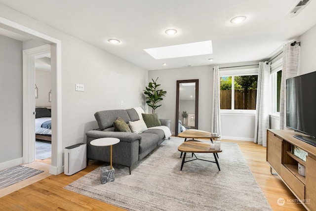 living room with light hardwood / wood-style floors and a skylight